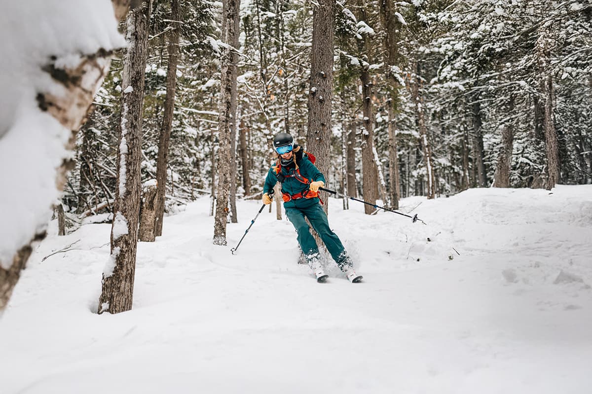 Skier in teal jacket carving through backcountry trails as part of Backyard Concept's commitment to protecting outdoor spaces