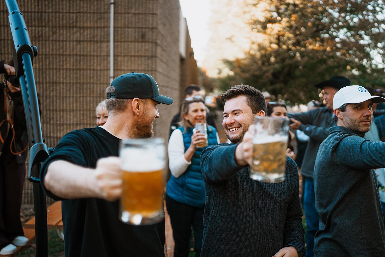 Coworkers holding beer steins in custom Patagonia vests and jackets share a toast.