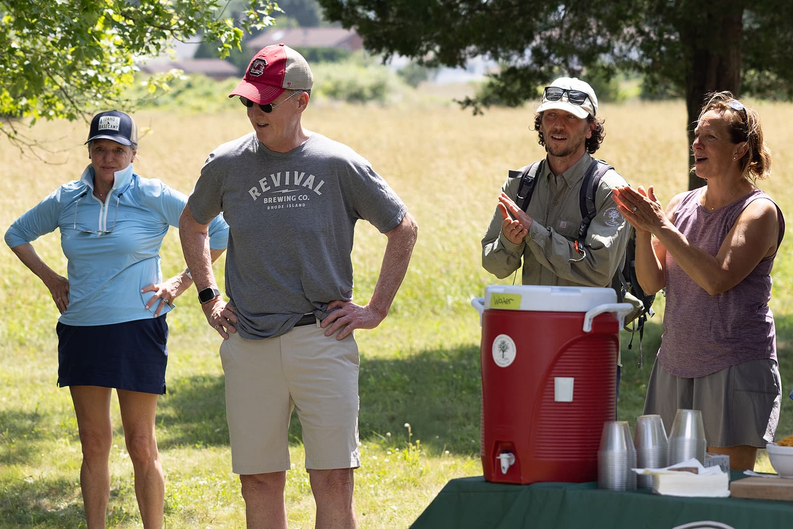 PK team at an outdoor event standing by a water cooler wearing custom tees and custom made hats.